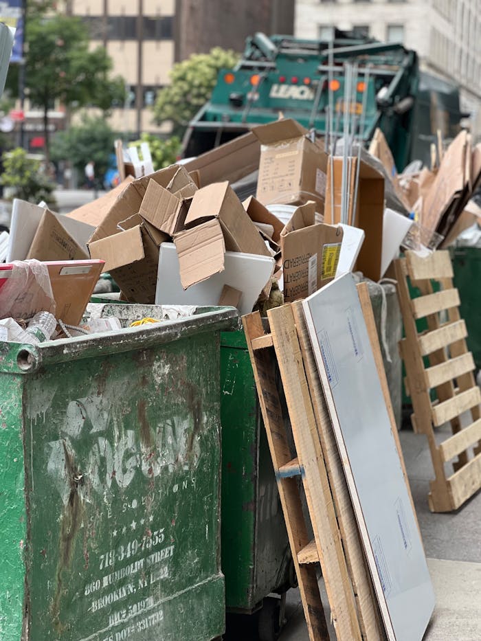 Piled cardboard boxes and waste in a city dumpster highlight urban recycling.