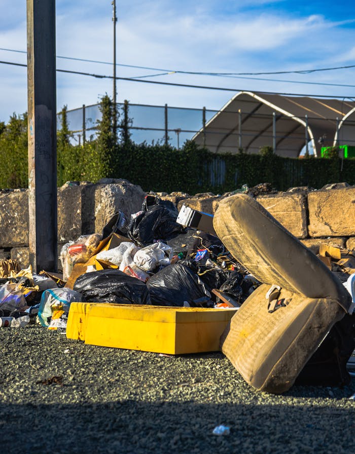Outdoor scene of a garbage pile including a discarded mattress and various waste materials.